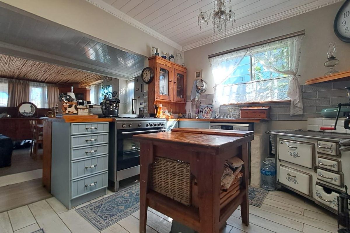 A rustic-style kitchen featuring timber cabinetry, wooden countertops, a freestanding oven, and a tiled backsplash, offering a warm and traditional aesthetic.
