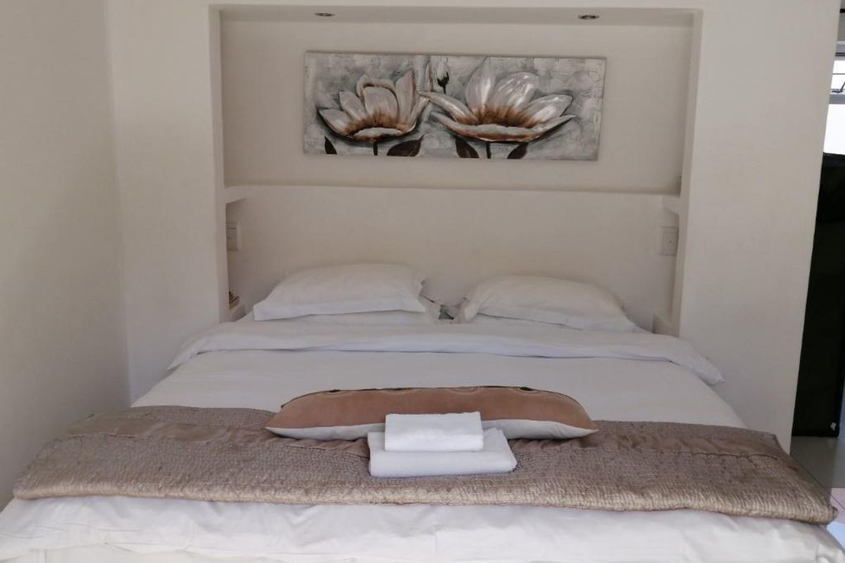 A well-maintained bedroom featuring a built-in recessed headboard niche with integrated downlighting.