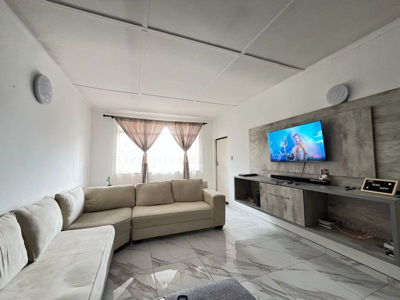 A bright living room featuring modern marble-look floor tiles and a custom built-in media console with integrated shelving.