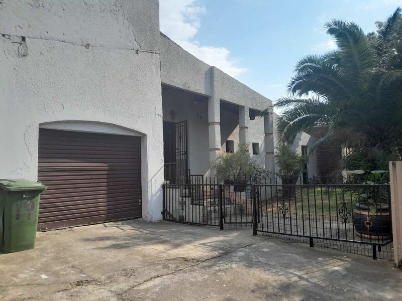 Front elevation of the house featuring a single roller garage door, covered porch area, and wrought iron perimeter fencing.