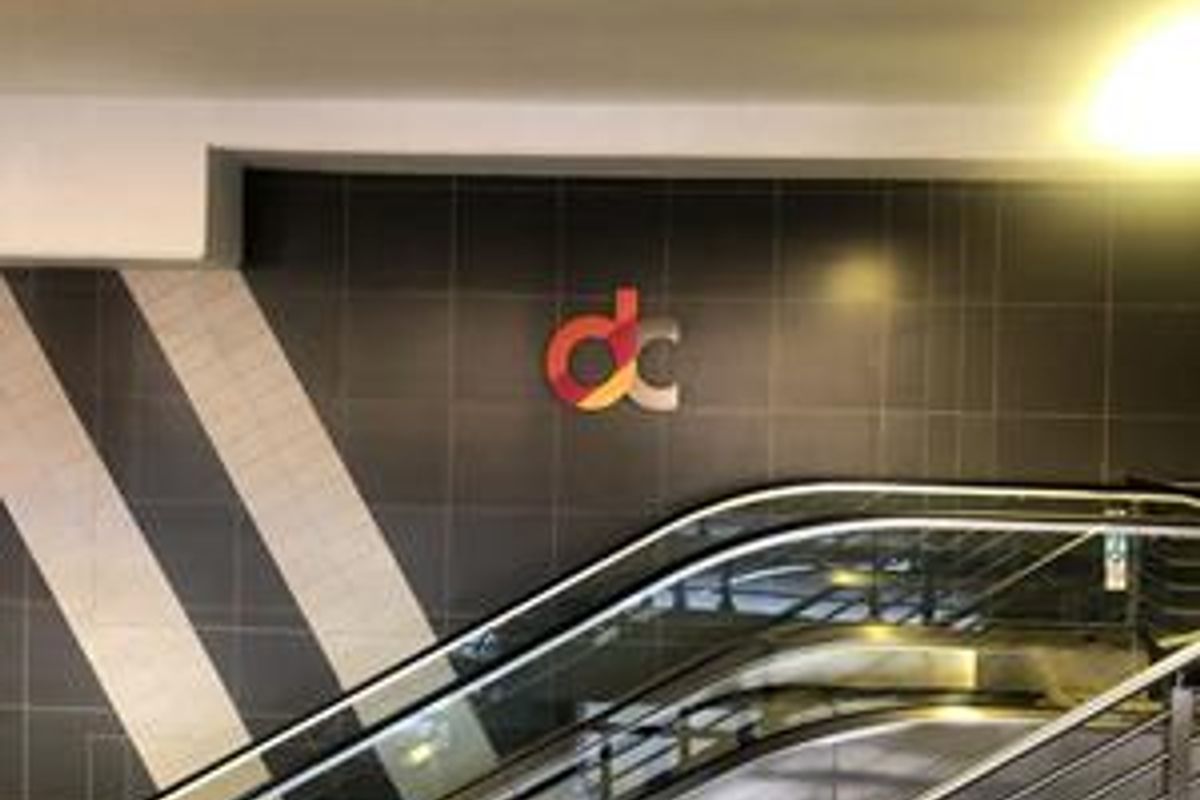 Interior view of a commercial building lobby featuring an escalator and modern tiled wall finishes.