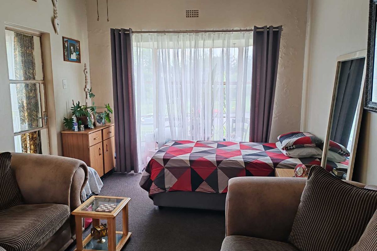 A bedroom featuring large windows with natural light, carpeted flooring, and access to an adjacent patio area.