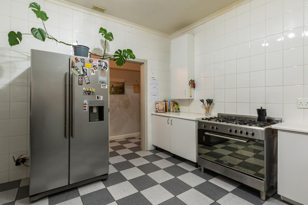 A functional kitchen featuring a gas stove, oven, tiled walls, and checkered flooring, offering a clean and practical workspace.