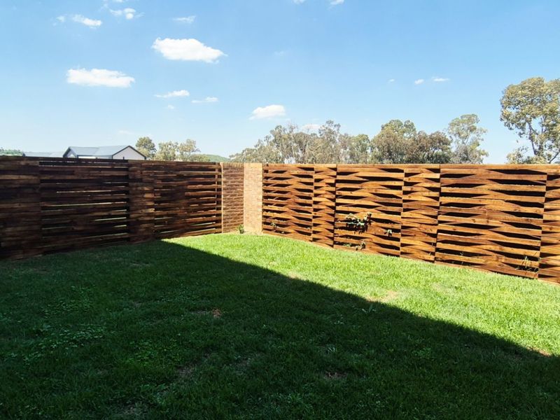 A private garden area featuring well-maintained lawn and decorative timber slat fencing with a central brick pillar.