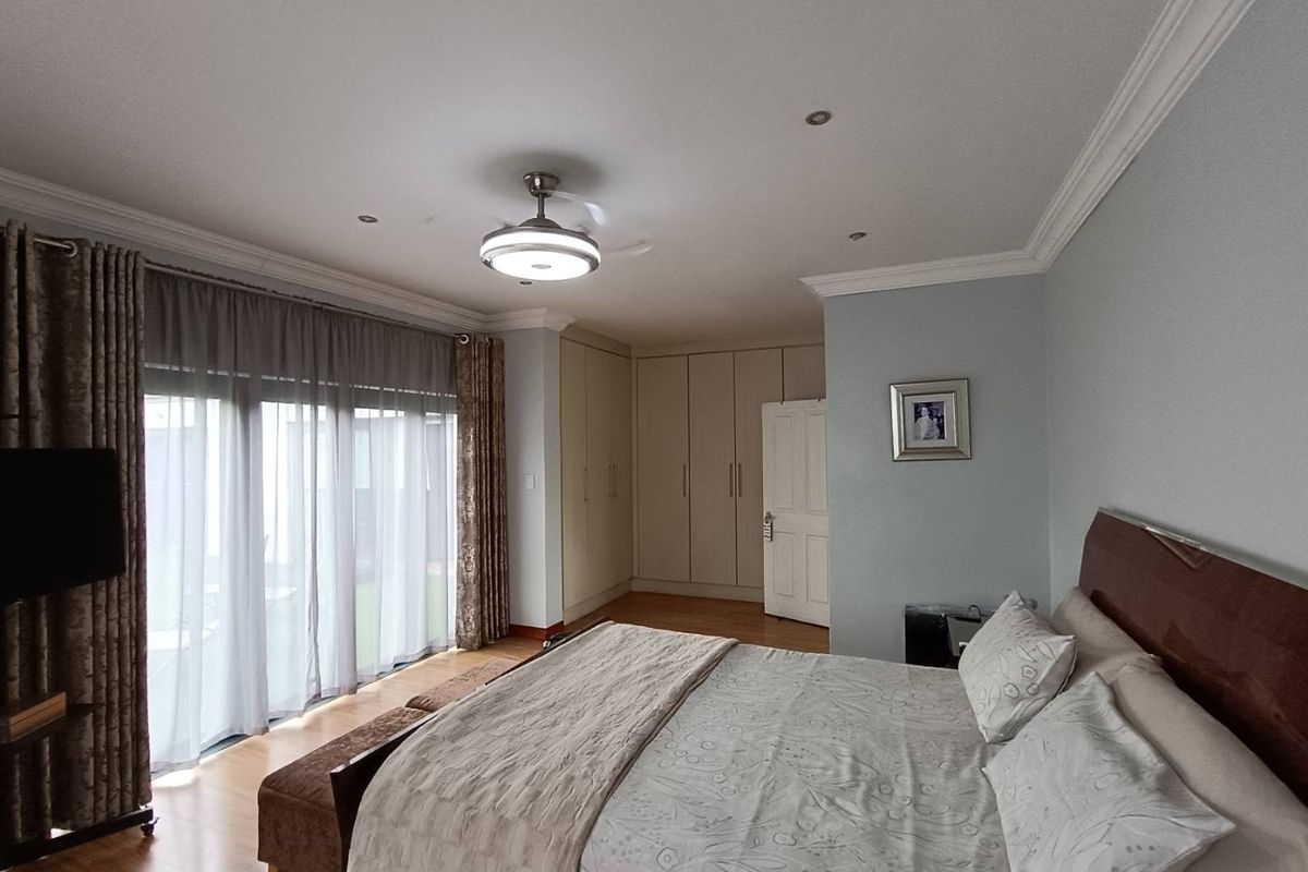 Spacious bedroom featuring built-in cupboards, laminate flooring, recessed ceiling lighting, and large sliding doors providing access to the outdoor area.
