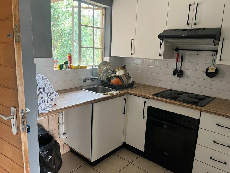 Compact kitchen featuring white cabinetry, wood-look laminate countertops, subway tile backsplash, and integrated appliances including an oven and hob.