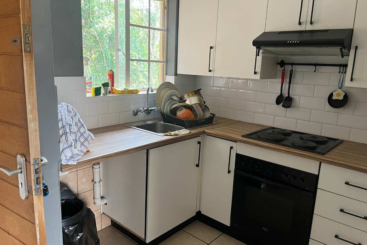 Compact kitchen featuring white cabinetry, wood-look laminate countertops, subway tile backsplash, and integrated appliances including an oven and hob.