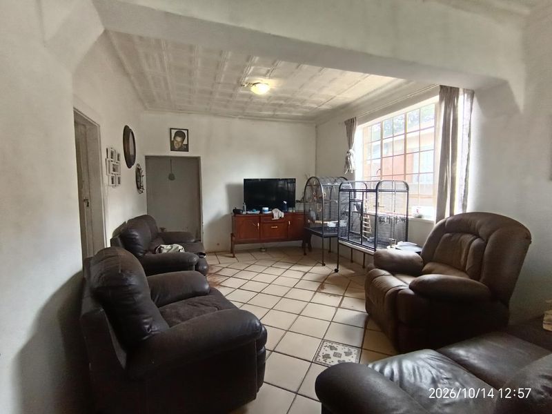 Spacious living room featuring tiled flooring and a textured ceiling, offering a functional layout with natural light from a large window.