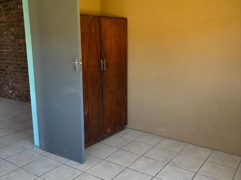 A simple bedroom featuring tiled flooring and neutral wall paint, providing a blank canvas for potential interior updates.
