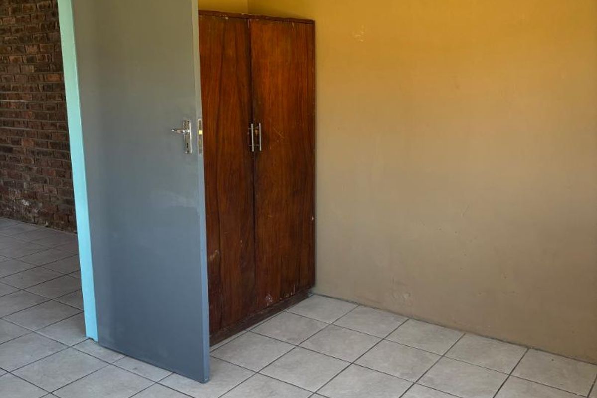 A simple bedroom featuring tiled flooring and neutral wall paint, providing a blank canvas for potential interior updates.