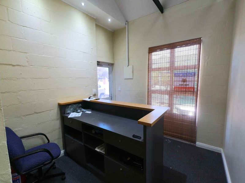 A functional office reception area featuring a built-in desk, recessed lighting, and exposed brick walls, providing a practical workspace for clients and staff.