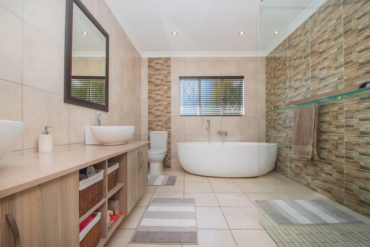 Modern bathroom featuring a freestanding bathtub, glass-enclosed shower, dual vanity with vessel sinks, and neutral tiled finishes.
