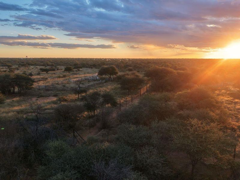 An expansive aerial view of the small holding landscape at sunset, showcasing the natural terrain and perimeter fencing.