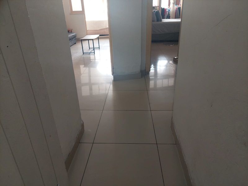 A view through a central hallway with tiled flooring, connecting to adjacent living and bedroom spaces.