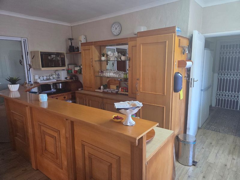 A kitchen area featuring extensive built-in wooden cabinetry and a breakfast bar, providing functional storage and prep space within the cottage.