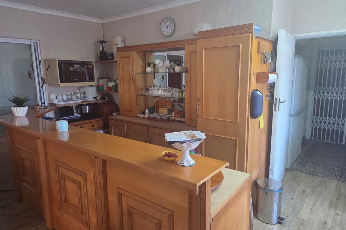 A kitchen area featuring extensive built-in wooden cabinetry and a breakfast bar, providing functional storage and prep space within the cottage.