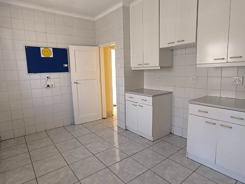 A functional kitchen space featuring white built-in cabinetry, fully tiled walls, and tiled flooring, offering a clean and neutral foundation for updates.