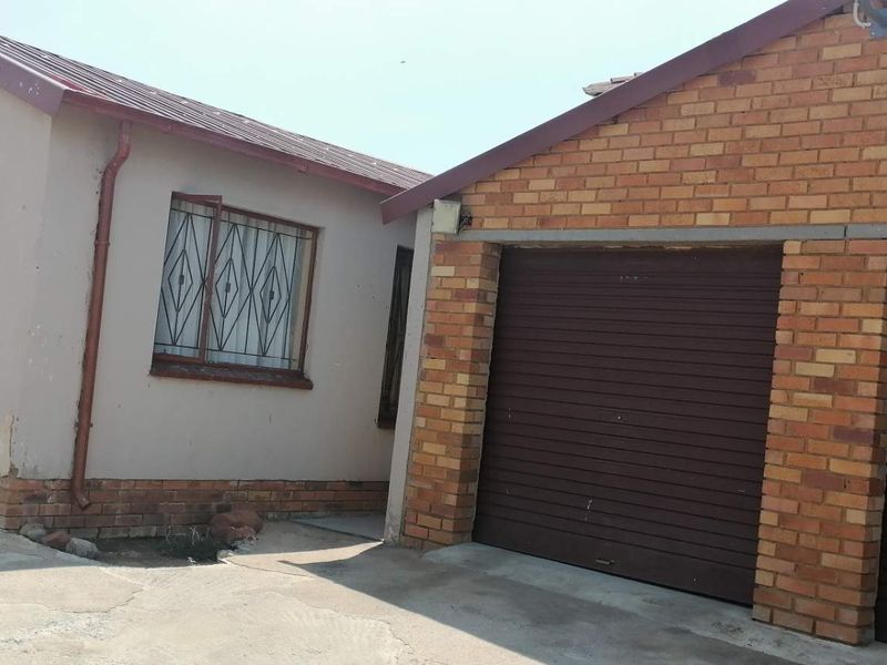 Exterior view of a residential property featuring a double garage with roller shutter doors and a concrete driveway.