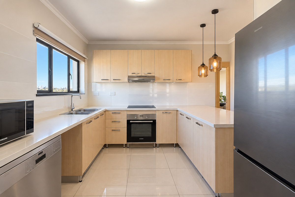 Modern kitchen featuring light-wood cabinetry, stone countertops, integrated appliances, and sleek tiled flooring with ample natural light.