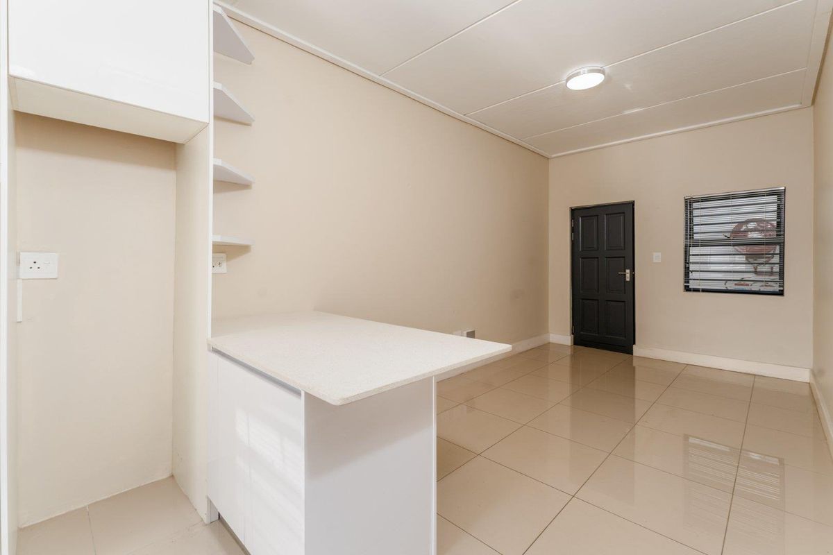 A clean, empty kitchen area featuring tiled flooring, built-in cabinetry with a stone countertop, and neutral wall finishes.