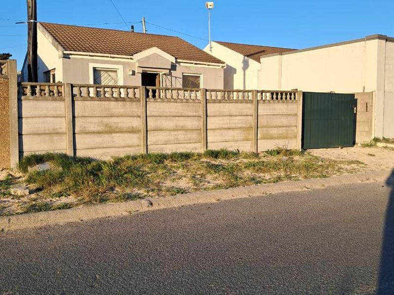 Front view of a residential property featuring a tiled roof, security bars, and a precast concrete boundary wall with a metal gate.
