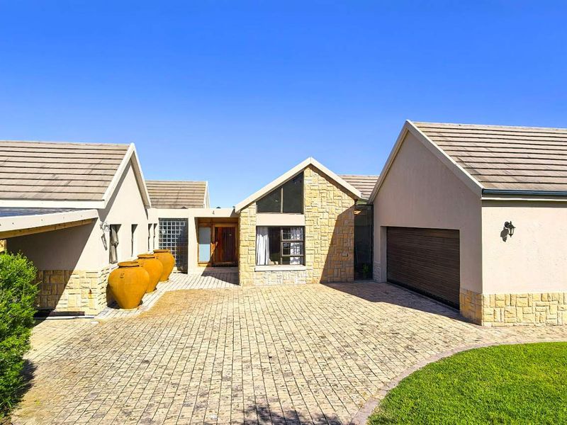 Front elevation of a modern house featuring a paved driveway, stone-clad facade, tiled roof, and an integrated double garage.