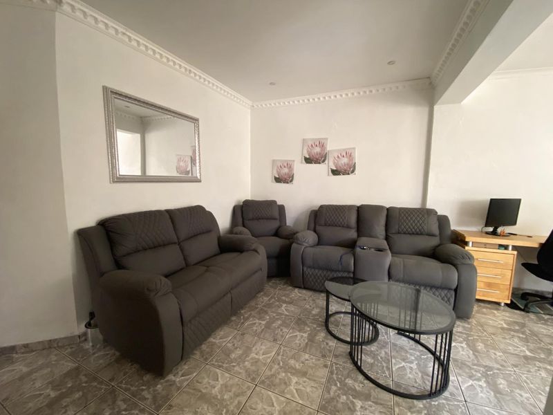 A living room featuring tiled flooring, decorative ceiling cornicing, and recessed downlighting, providing a neutral base for interior design.