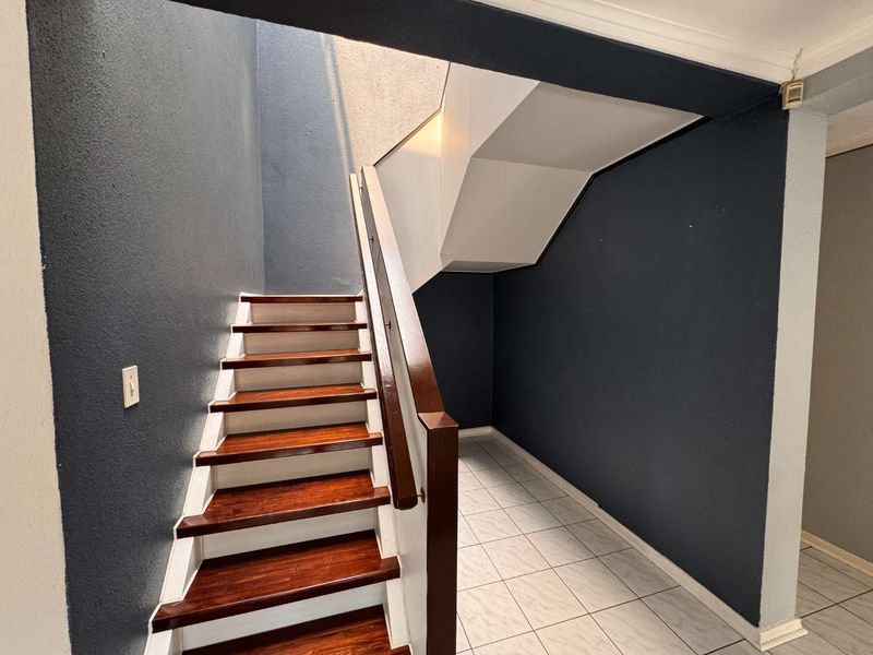An inviting entrance area featuring a staircase with polished wooden treads and a modern dark-toned wall finish.