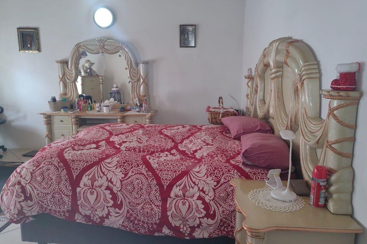 A bedroom featuring tiled flooring and a wall-mounted light fixture, providing a functional space for rest.