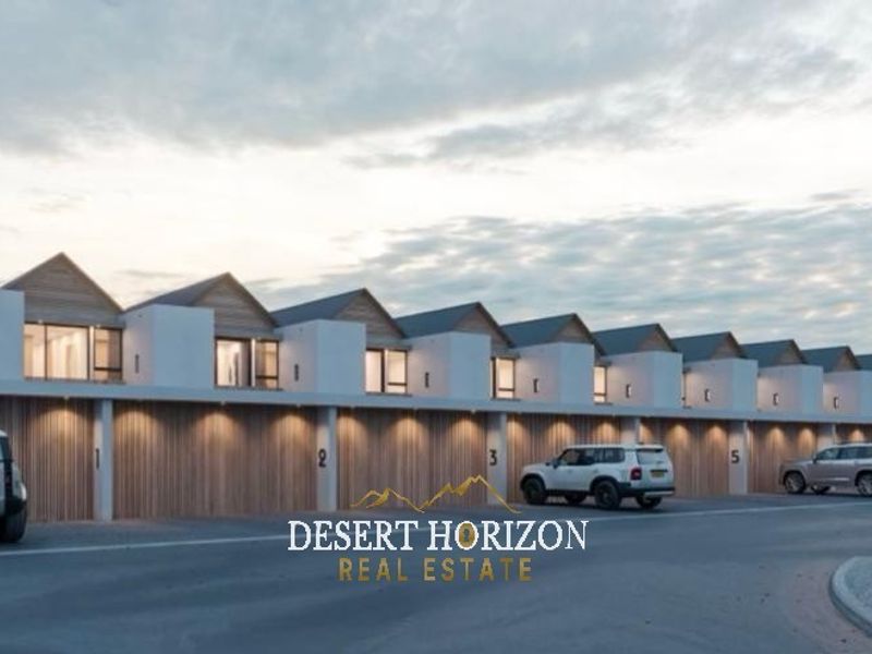 Modern townhouse complex featuring a row of garages with contemporary architectural design, pitched rooflines, and integrated exterior lighting.