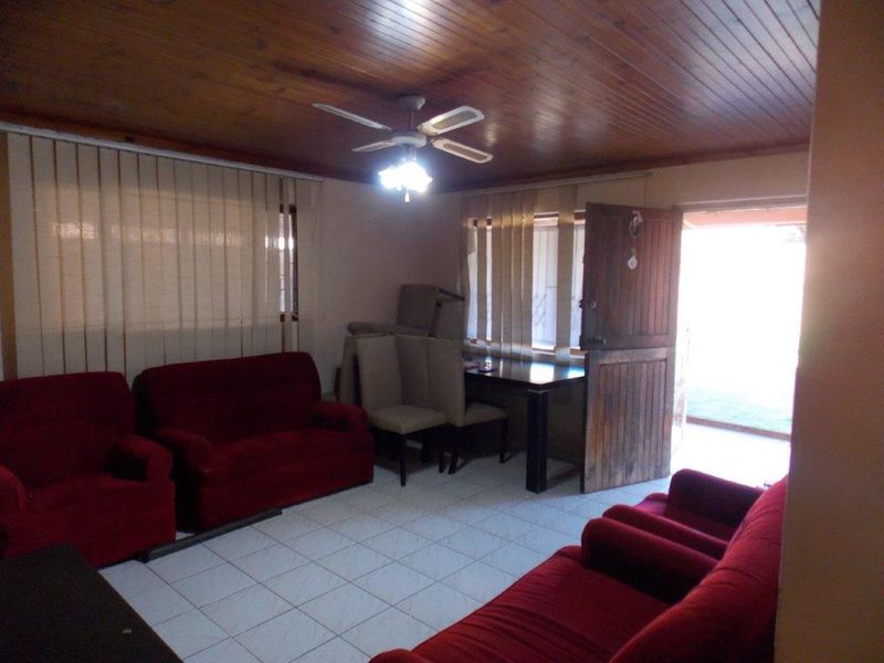 A living room featuring tiled flooring, a wooden tongue and groove ceiling with a ceiling fan, and a stable-style wooden entrance door.