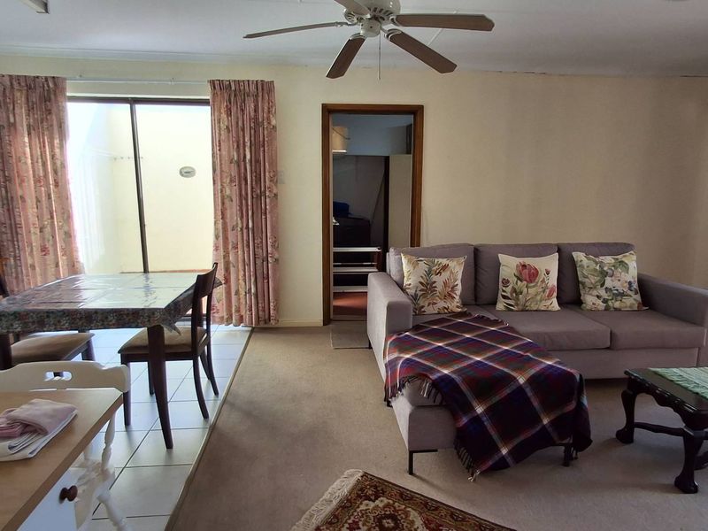 Open plan living and dining area featuring a ceiling fan, tiled and carpeted flooring, and sliding glass door access to an outdoor space.