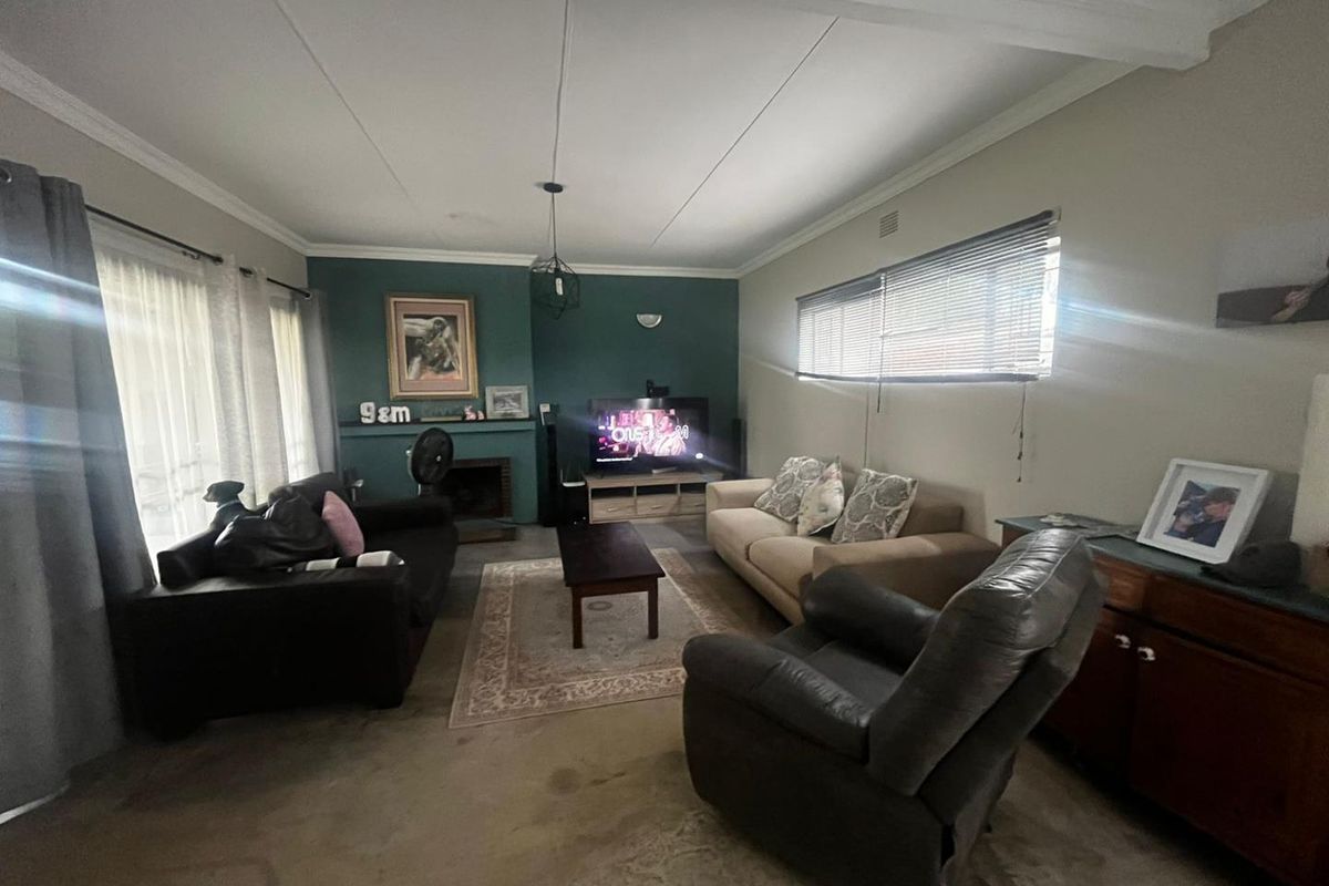 A comfortable living room featuring a fireplace, neutral walls with a teal accent wall, and large windows allowing for natural light.