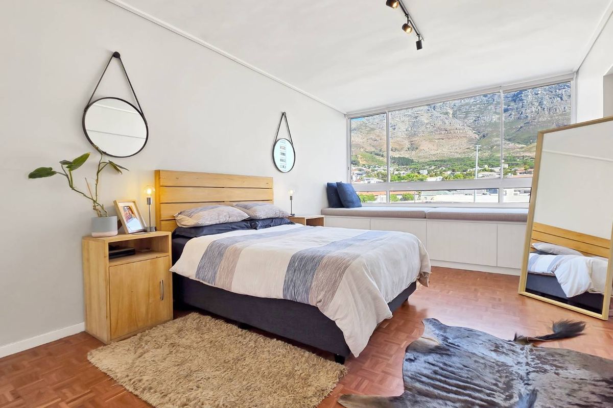Bright bedroom featuring parquet flooring, a built-in window seat with storage, and large windows offering scenic mountain views.