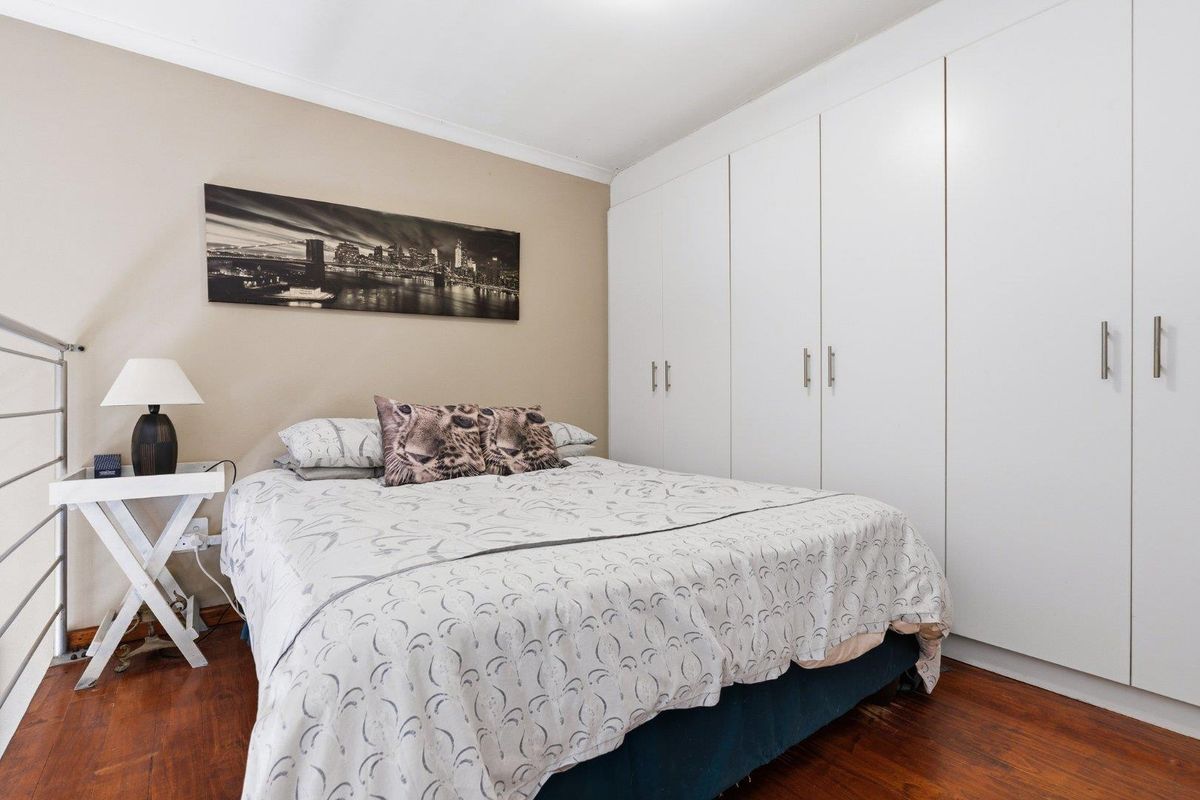 A well-maintained bedroom featuring extensive built-in cupboards and warm laminate flooring, providing ample storage and a comfortable living space.