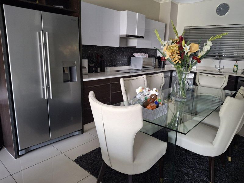 Modern open-plan kitchen and dining area featuring sleek cabinetry, stone countertops, and high-quality tiled flooring, creating a functional and contemporary living space.