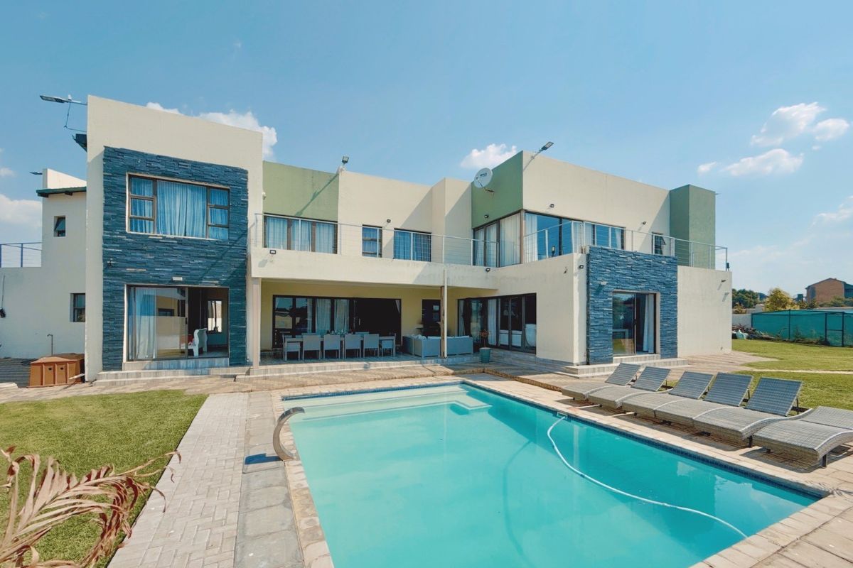 Rear view of a modern double-story home featuring a swimming pool, paved patio area, and stone-clad architectural accents.