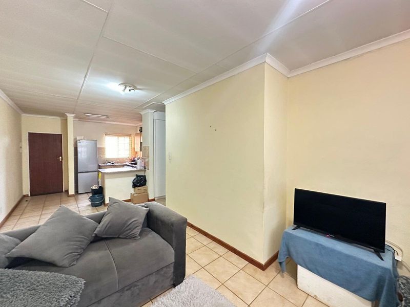 Open plan living area featuring tiled flooring and a connected kitchen space with built-in cabinetry and sink.