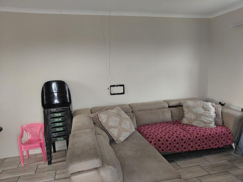 A living room area featuring tiled flooring and coved cornicing, with visible wall-mounted television bracket and exposed wiring.