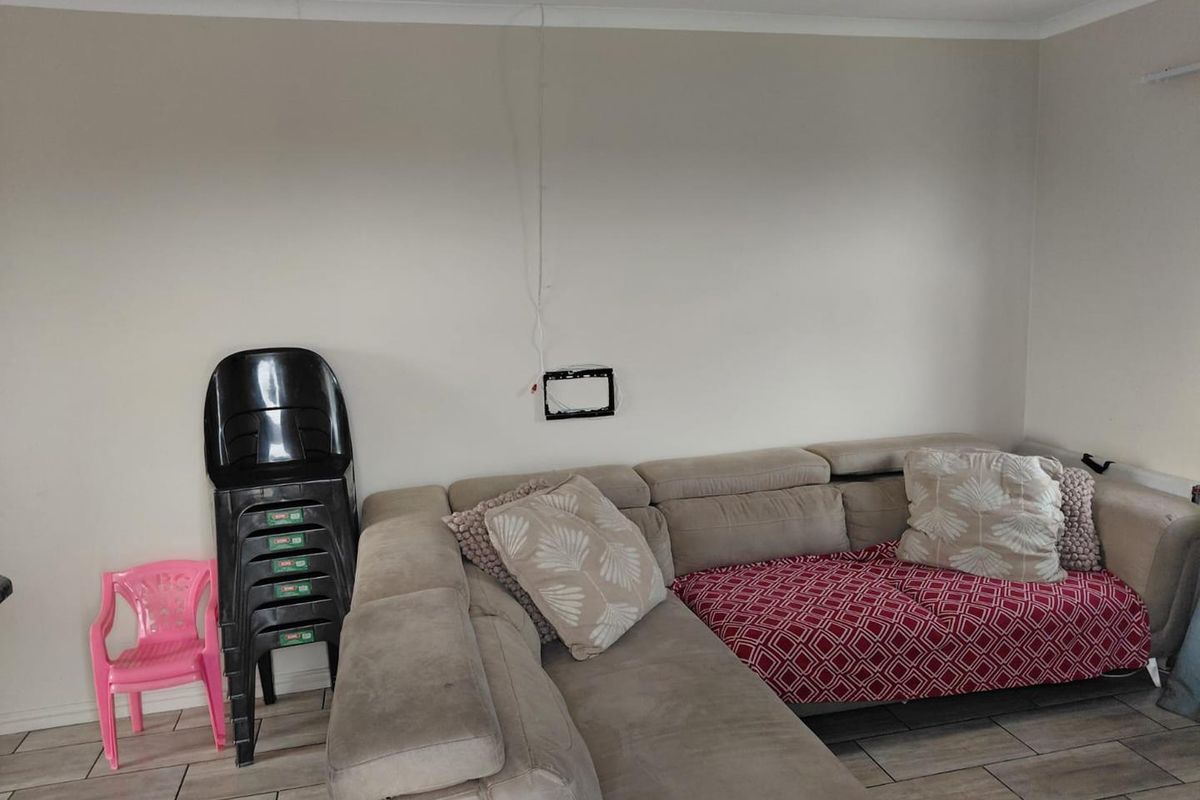 A living room area featuring tiled flooring and coved cornicing, with visible wall-mounted television bracket and exposed wiring.