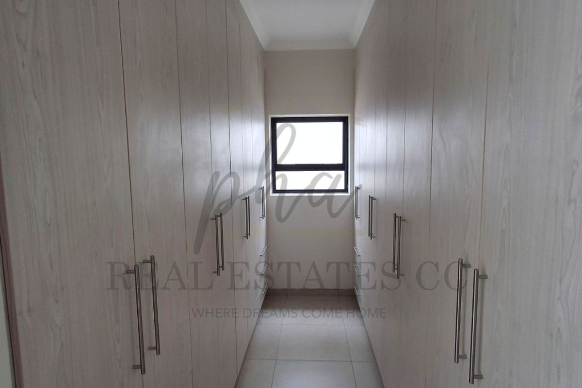 A walk-in closet or dressing area featuring extensive floor-to-ceiling built-in cabinetry with light wood-grain finish and modern metal handles.