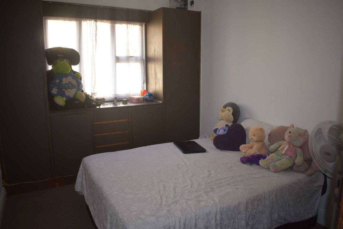 A bedroom featuring built-in dark wood cabinetry and a window with integrated storage shelving.