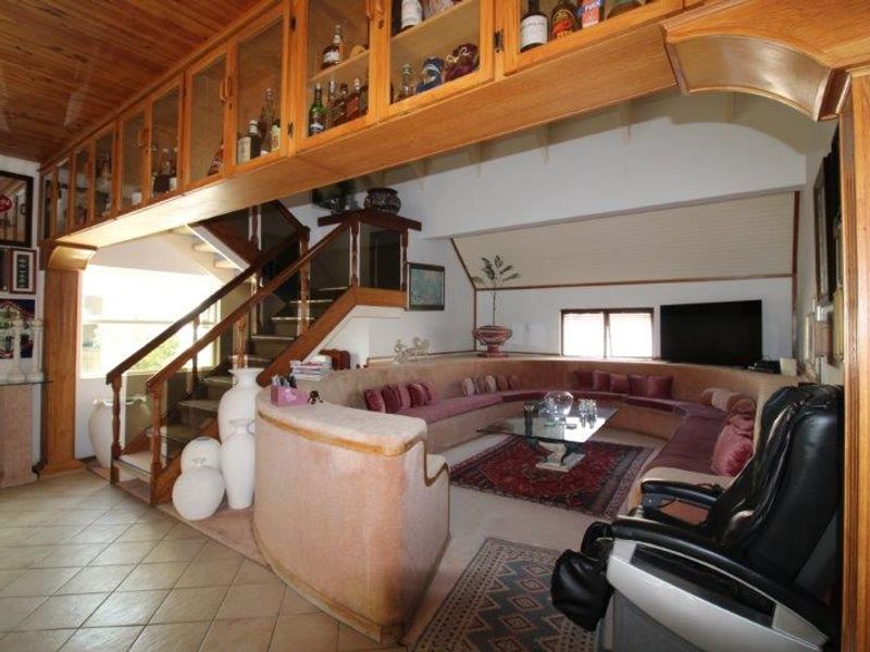 Spacious living area featuring a unique built-in curved seating arrangement, timber ceiling, and extensive overhead cabinetry, connected to an internal staircase.