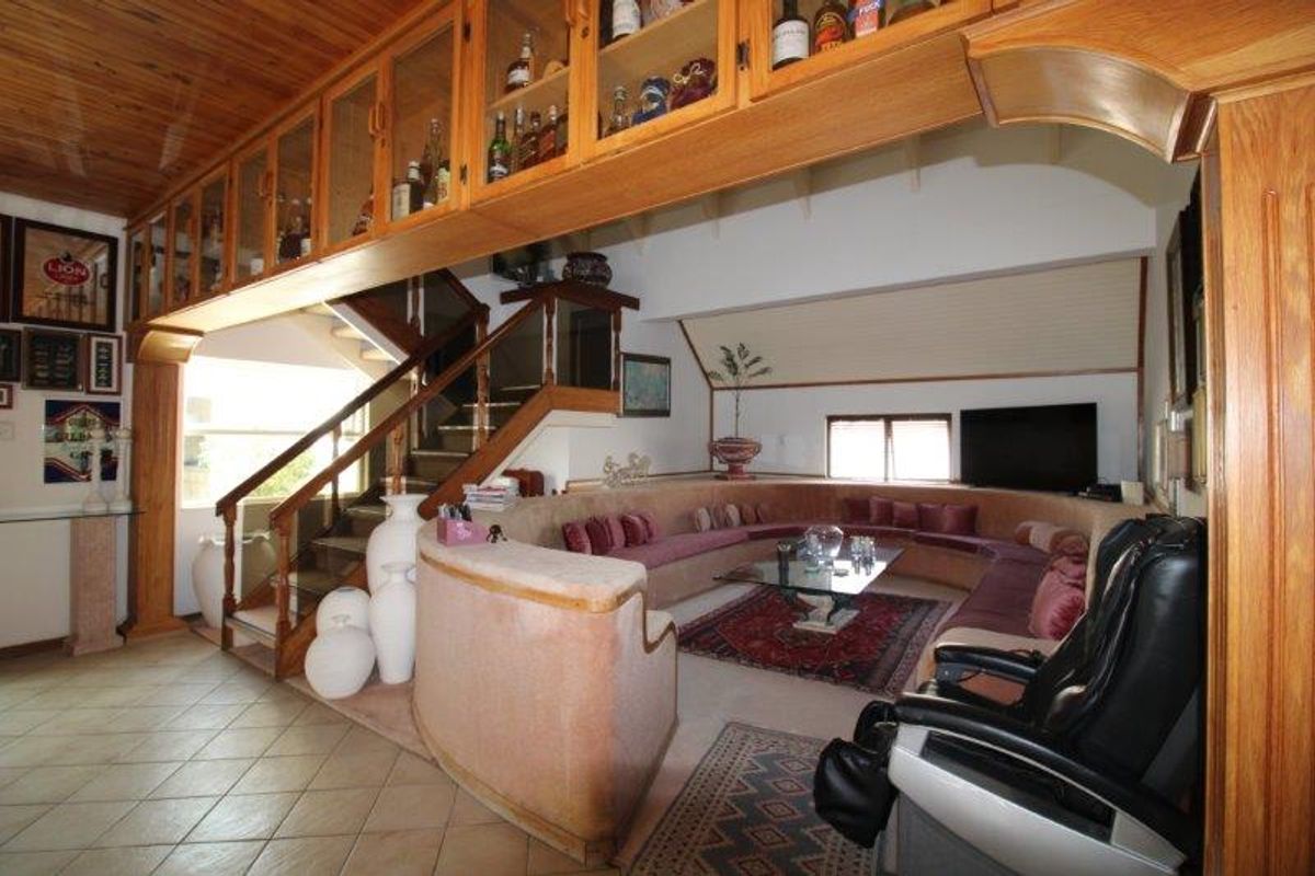 Spacious living area featuring a unique built-in curved seating arrangement, timber ceiling, and extensive overhead cabinetry, connected to an internal staircase.