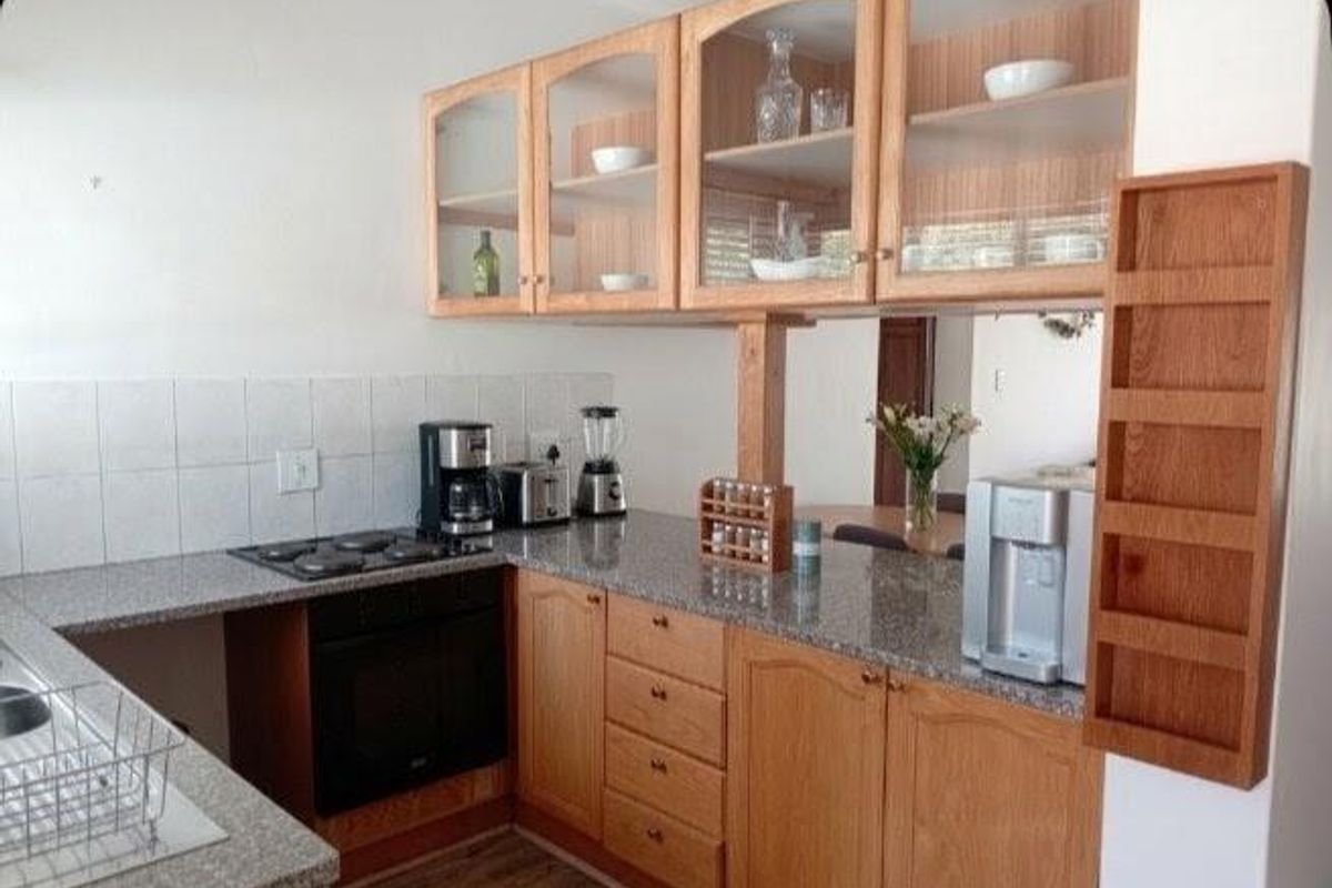 A functional kitchen featuring wooden cabinetry, granite countertops, a built-in oven, and a tiled backsplash with a convenient pass-through window to the dining area.