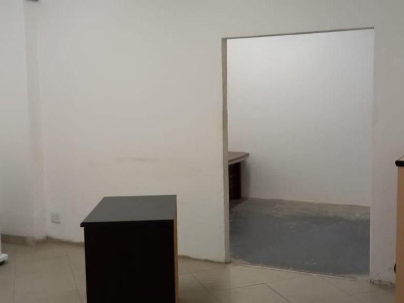 A functional office space featuring tiled flooring and a connecting internal doorway, suitable for a professional workspace or administrative area.