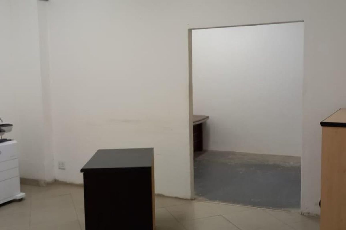 A functional office space featuring tiled flooring and a connecting internal doorway, suitable for a professional workspace or administrative area.