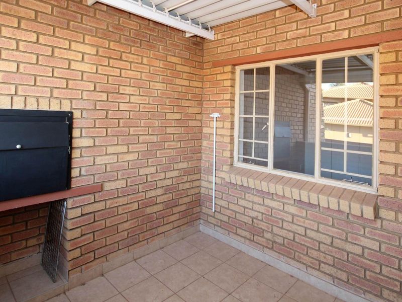 A covered patio area featuring exposed brick walls, a built-in braai, and tiled flooring, offering a functional outdoor space.