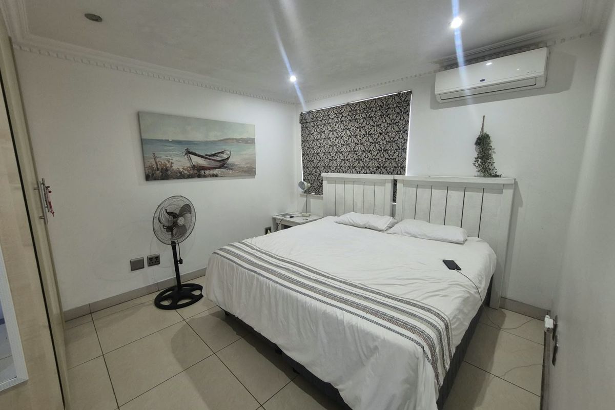A well-maintained bedroom featuring tiled flooring, crown molding, recessed lighting, and a wall-mounted air conditioning unit.