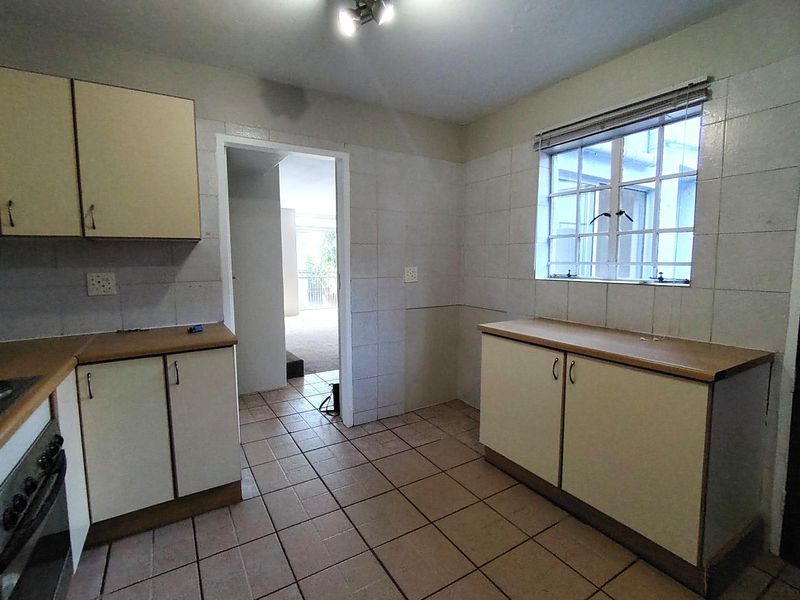 A functional, empty kitchen featuring tiled flooring, built-in cabinetry, and a built-in oven, offering a blank canvas for potential modern updates.